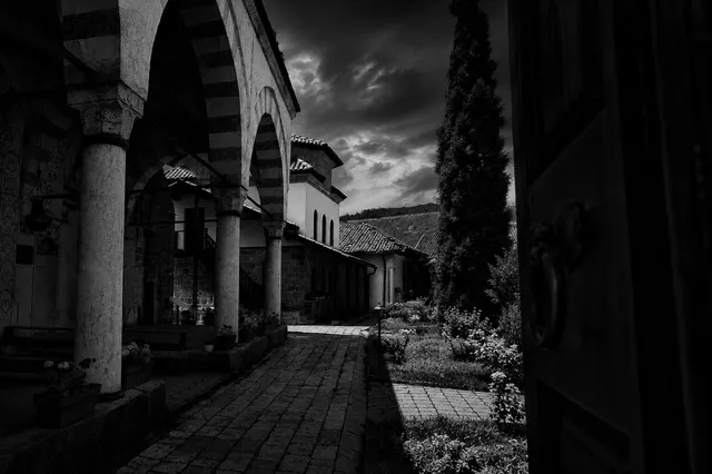 The Hadum Mosque's arched, painted portico at dusk, a cypress beside it.