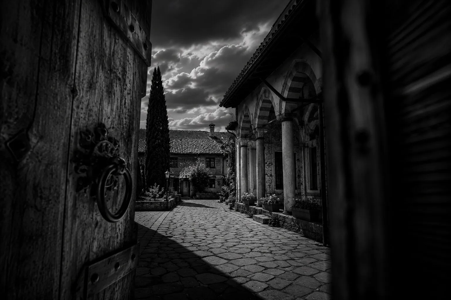 The Hadum Mosque's courtyard seen through the heavy bazaar gate, a cypress beyond.