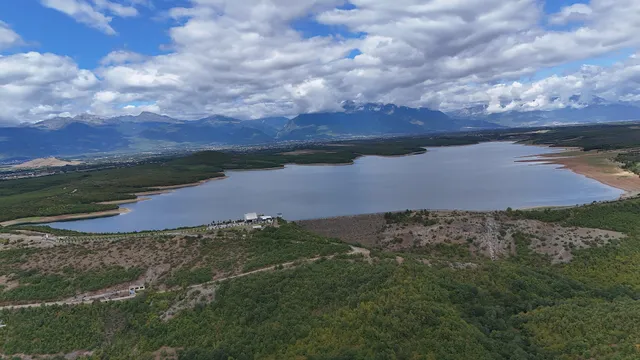 Radoniq reservoir seen from the air, its blue arms among green hills.